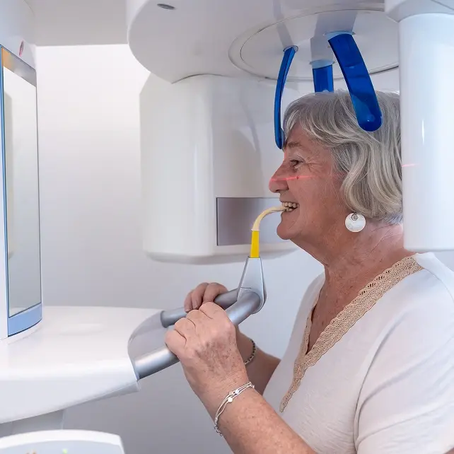 Woman positioned for dental imaging scan using panoramic X-ray equipment at Panama City dental practice.