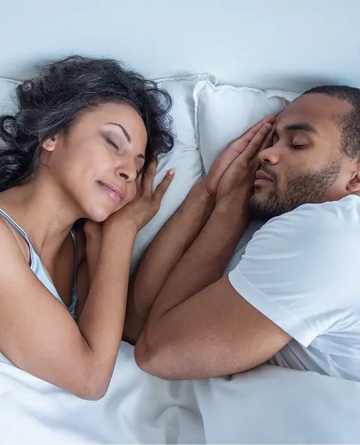 Couple sleeping peacefully in bed, illustrating restful sleep after sleep apnea treatment.